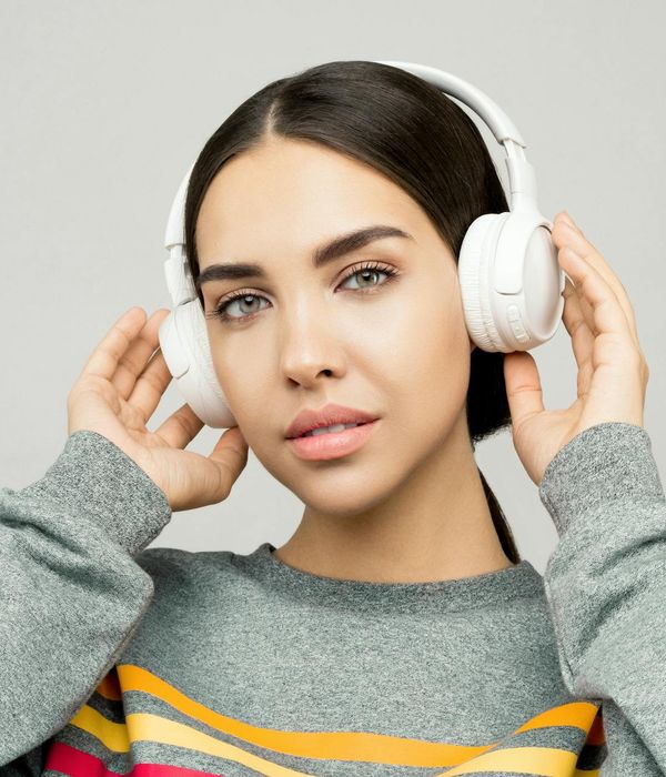 Young woman looking into the distance with a calm expression in a dark studio setting.